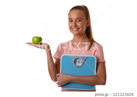 Young attractive girl showing green apple on her palm and holding weighing scale. Isolated over white background Young attractive girl showing green apple on her palm and holding weighing scale. Isolated over white background 121123826