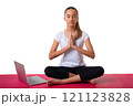 Inner power. Young woman sitting in pose of lotus and putting her palms together on her chest area with laptop on yoga mat, isolated on white background 121123828