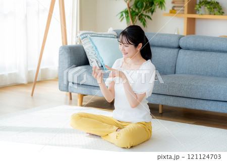 部屋でスマホを操作する若い女性 121124703