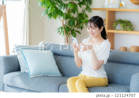 部屋でスマホを操作する若い女性 部屋でスマホを操作する若い女性 121124707