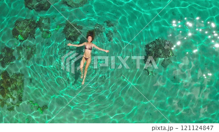 Swimming in clear turquoise waters, a young woman enjoys the sun and coral reefs from above, embodying relaxation and exploration. Let the seascape inspire your wanderlust Swimming in clear turquoise waters, a young woman enjoys the sun and coral reefs from above, embodying relaxation and exploration. Let the seascape inspire your wanderlust 121124847