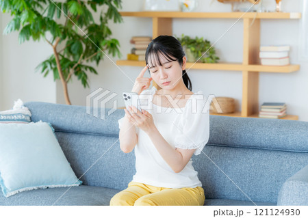 部屋でスマホを操作する若い女性 部屋でスマホを操作する若い女性 121124930