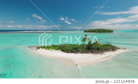 Aerial view of a woman enjoying a tropical paradise as she walks on a sandbank that connects a small island to a larger one Aerial view of a woman enjoying a tropical paradise as she walks on a sandbank that connects a small island to a larger one 121124938