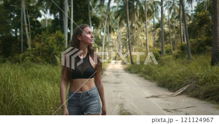 Beautiful woman walk jungle forest back view. Hiking trail and green coconuts. Beautiful path among large palm trees. Outdoor lifestyle travel, summer holiday vacation to tropical island. Slow motion 121124967