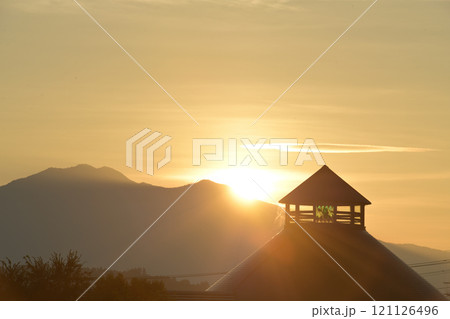 北杜市白州町、茅ヶ岳から昇る朝日が道の駅はくしゅうの三角屋根を照らす 121126496