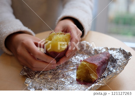 ストーブで焼いた焼き芋を割る小学生の手 121127263