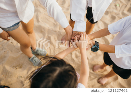Beach teamwork with a happy family. Hands together in a stack symbolizing success and achievement. Parents and children unite in nature emphasizing community motivation and togetherness 121127461