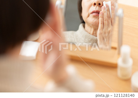 鏡の前で基礎化粧品を使ってスキンケアするミドル〜シニア女性 121128140