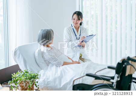 介護施設で暮らすシニア女性と白衣の女性 介護施設で暮らすシニア女性と白衣の女性 121128913