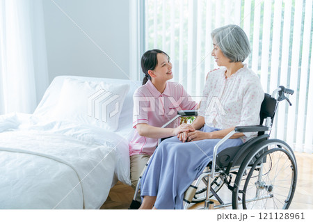 介護施設で暮らすシニア女性と若い介護士 121128961