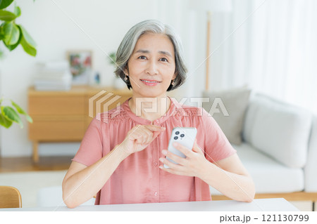 リビングでスマホを操作するシニア女性 リビングでスマホを操作するシニア女性 121130799