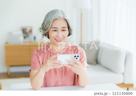 リビングでスマホを操作するシニア女性 リビングでスマホを操作するシニア女性 121130800