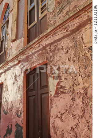 Exterior of an old building with peeling paint. Architecture details of an ancient, weathered rustic residential build with vintage wooden doors and windows in Santa Cruz de La Palma Exterior of an old building with peeling paint. Architecture details of an ancient, weathered rustic residential build with vintage wooden doors and windows in Santa Cruz de La Palma 121132196