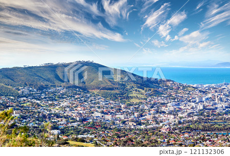 Copy space with cloudy blue sky over the view of a coastal city seen from Signal Hill in Cape Town South Africa. Scenic panoramic landscape of buildings in an urban town along the mountain and sea 121132306