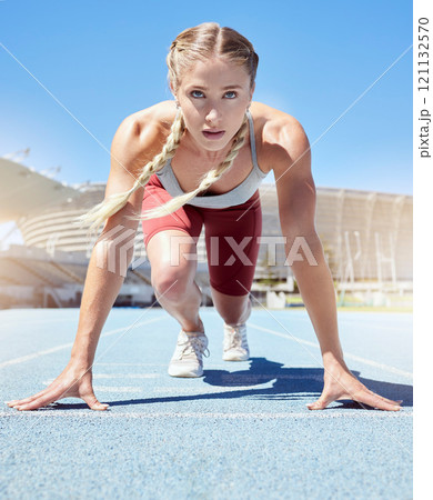Serious female athlete at the starting line in a track race competition at the stadium. Fit sportswoman mentally and physically prepared to start running at the sprint line or starting block 121132570