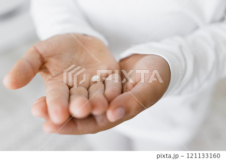 Small child hands holding baby tooth. Caucasian child, wearing white clothes, shows excitement about losing first teeth. Image embodies childhood milestones and growth. 121133160