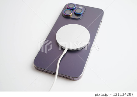 BANGKOK,THAILAND. MARCH 29 2024 MagSafe wireless magnetic charger back of iPhone 14 Pro Max, modern equipment of mobile phone. BANGKOK,THAILAND. MARCH 29 2024 MagSafe wireless magnetic charger back of iPhone 14 Pro Max, modern equipment of mobile phone. 121134297