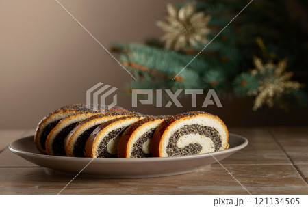 Poppy seed roll pieces on a background of Christmas tree. 121134505