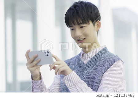 スマホで動画鑑賞する若い男性 ビデオ通話 スマホで動画鑑賞する若い男性 ビデオ通話 121135465