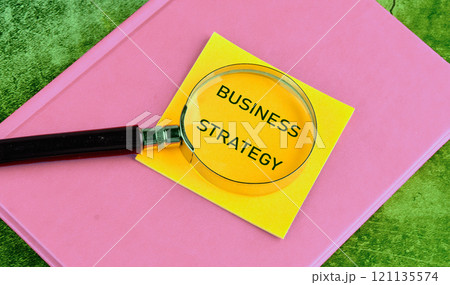 Business planning concept. BUSINESS STRATEGY on yellow paper through a magnifying glass close-up, top view Business planning concept. BUSINESS STRATEGY on yellow paper through a magnifying glass close-up, top view 121135574