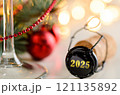 sparkling wine or champagne cork on table with christmas or new year 2025 blurred background and decorated fir-tree 121135892