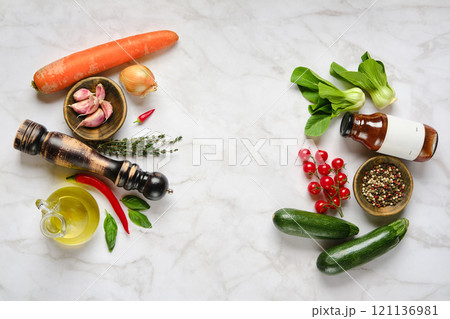 Fresh vegetables and herbs arranged on a marble surface for meal preparation in a cozy kitchen 121136981