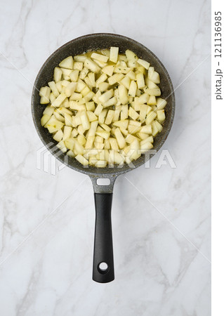 Chopped green pears in a frying pan ready for cooking on a marble kitchen countertop Chopped green pears in a frying pan ready for cooking on a marble kitchen countertop 121136985