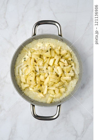 Creamy rice dish with diced pears and herbs in a silver pot on a marble countertop Creamy rice dish with diced pears and herbs in a silver pot on a marble countertop 121136986