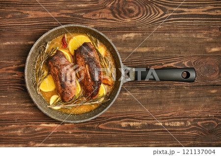 Savory roasted duck breasts with herbs and citrus in a frying pan 121137004