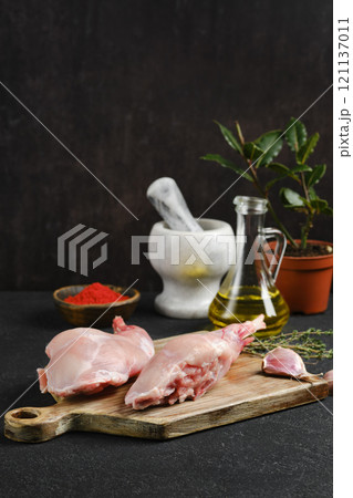 Preparation of fresh rabbit meat with herbs and spices on wooden cutting board Preparation of fresh rabbit meat with herbs and spices on wooden cutting board 121137011