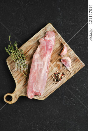 Raw rabbit tenderloin prepared with garlic and thyme on a wooden cutting board 121137014