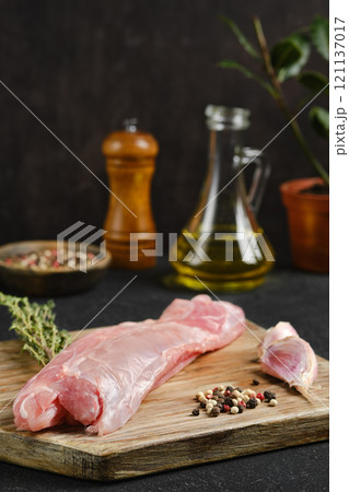 Fresh rabbit tenderloin on a wooden cutting board with herbs and spices in a kitchen setting Fresh rabbit tenderloin on a wooden cutting board with herbs and spices in a kitchen setting 121137017