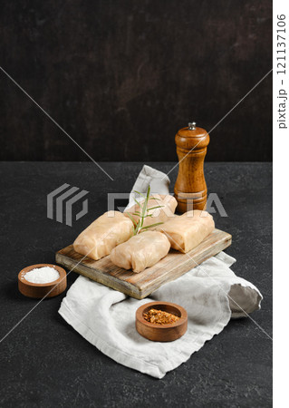 Cabbage spring rolls stuffed with meat ready for cooking on a wooden board with spices 121137106