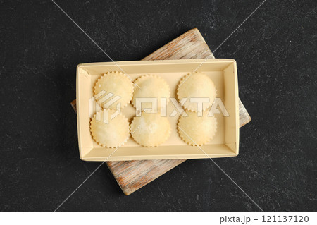 Homemade ravioli placed in a beige tray on a wooden cutting board in a kitchen setting Homemade ravioli placed in a beige tray on a wooden cutting board in a kitchen setting 121137120
