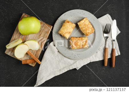 Delicious apple-filled crepes served with fresh fruit and cinnamon on a rustic table Delicious apple-filled crepes served with fresh fruit and cinnamon on a rustic table 121137137