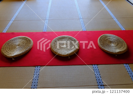 緋毛氈に置かれた丸座布団 121137400