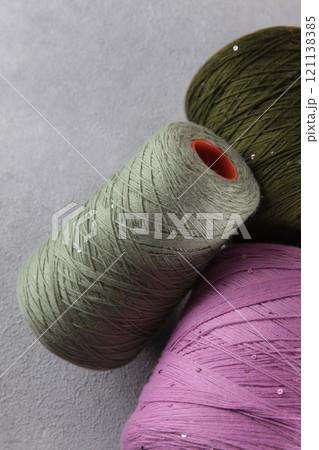 Multicolored wool yarn on gray background. Wool yarn for hand knitting. Yarn on bobbins. Multicolored wool yarn on gray background. Wool yarn for hand knitting. Yarn on bobbins. 121138385