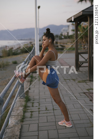 A young woman is actively and dynamically stretching her body by the beautiful seaside 121138841