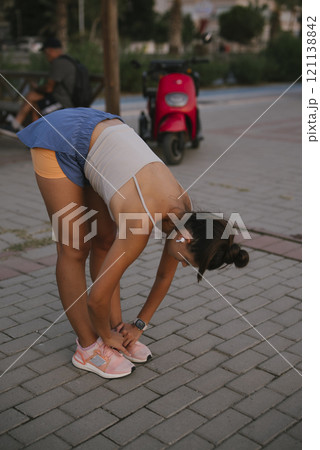 A woman is stretching outdoors while clad in her athletic wear, embracing nature and fitness 121138842