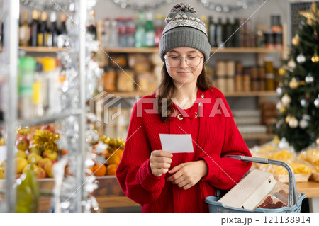 Teenage girl chooses food, fruits and sweets from pre-prepared list Teenage girl chooses food, fruits and sweets from pre-prepared list 121138914