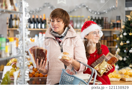 Visiting store on New Years Eve, woman with girl is looking at something on shelf of showcase. 121138929