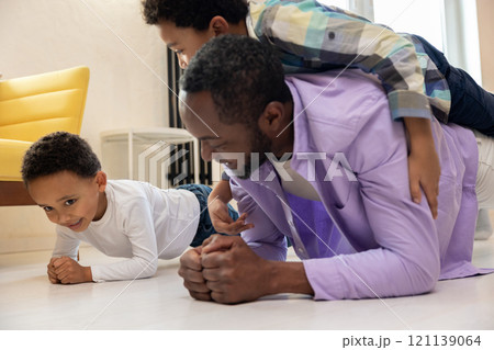 Dark-skinned father playing with his kids and carrying them on his back 121139064