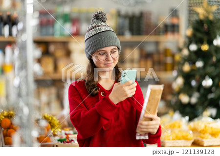 Teenage girl checks expiration date of nougat - scans QR code on label with smartphone Teenage girl checks expiration date of nougat - scans QR code on label with smartphone 121139128