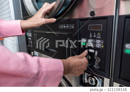 Close up picture of female hand programming washing machine 121139138