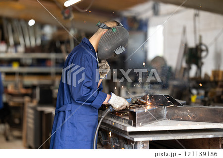 During manufacture of product, man employee works with welding machine During manufacture of product, man employee works with welding machine 121139186