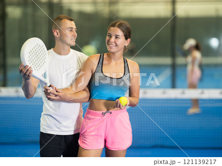 Man teaching young woman to hold racket 121139217