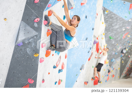 Sporty woman training at bouldering gym without special climbing equipment 121139304