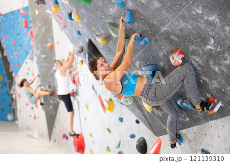 Young girl climbing on artificial rock wall in rock-climbing gym 121139310