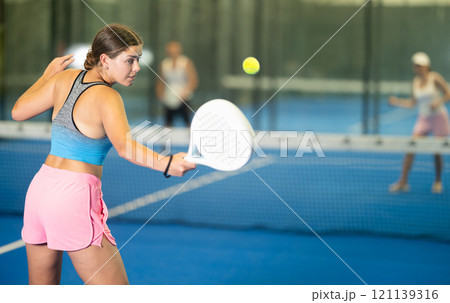 Portrait of girl paddle tennis player during friendly doubles couple match at court 121139316