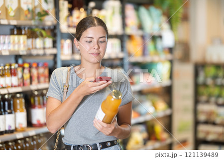 Female shopper scanning QR code on juice bottle in store 121139489